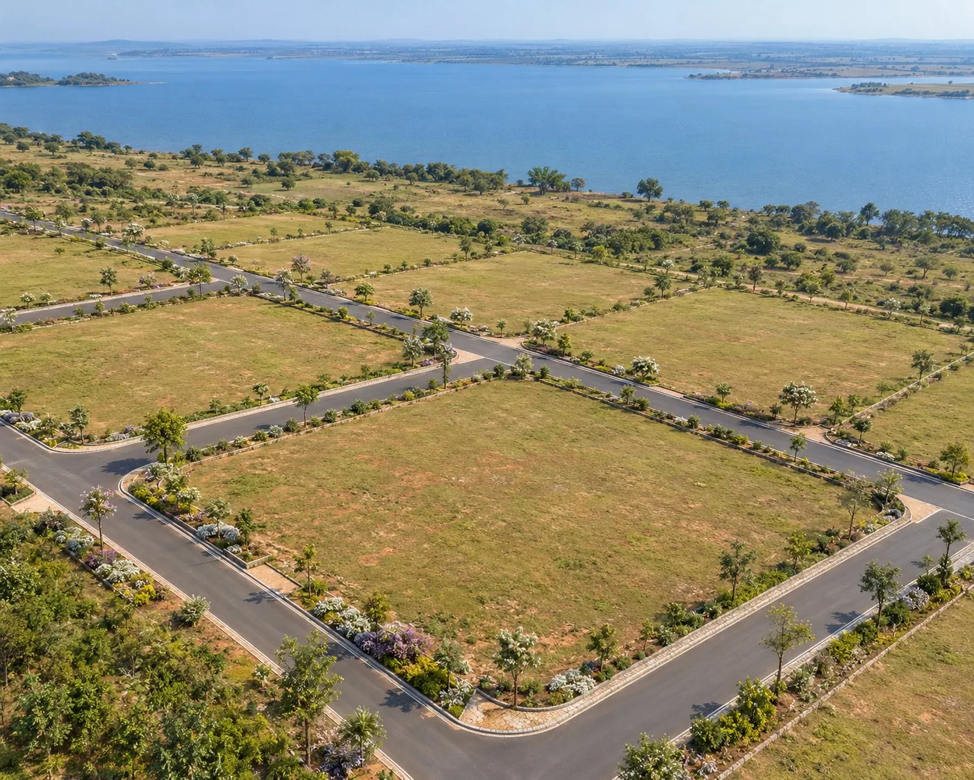 Concept visualisation of an aerial view of open residential plots framed by landscaped internal roads, with the lake beyond